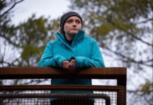 Alexa Battler leaning on a metal fence, wearing a blue winter jacket and a toque.